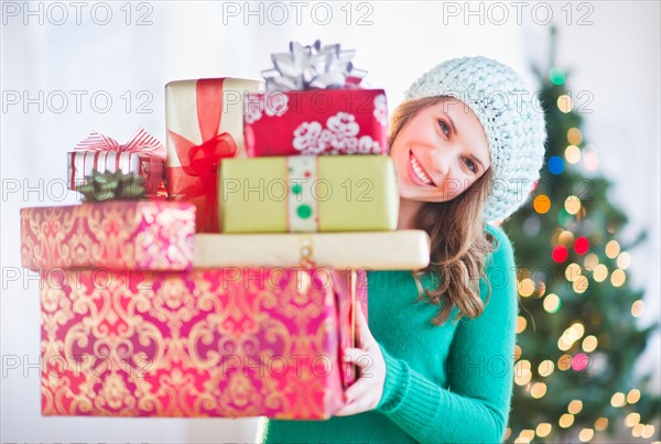 Young woman with stack of colorful Christmas gifts. Photo : Daniel Grill