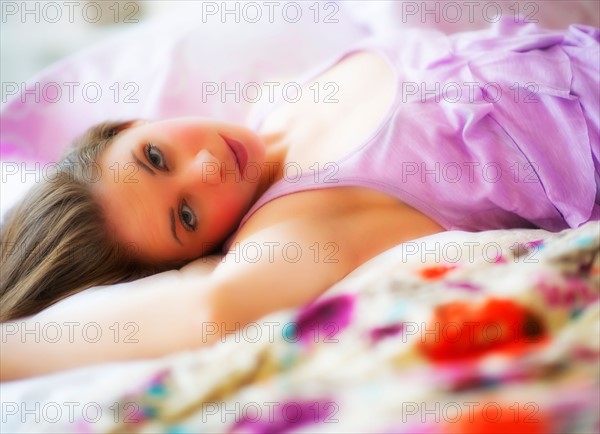 Young attractive woman lying on bed. Photo : Daniel Grill