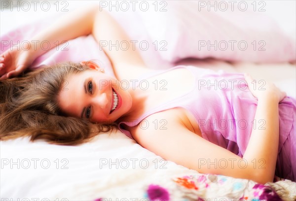 Young attractive woman lying on bed. Photo : Daniel Grill
