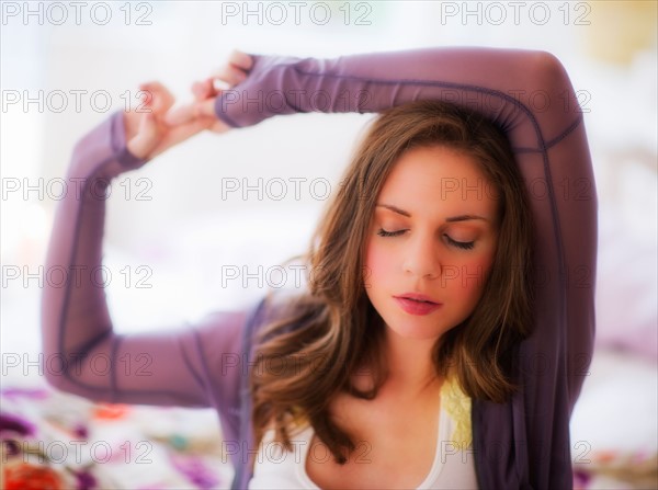 Young woman stretching on bed. Photo : Daniel Grill