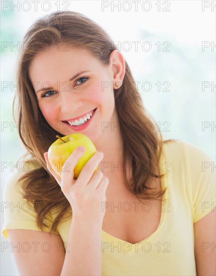 Portrait of smiling young woman holding apple. Photo : Daniel Grill