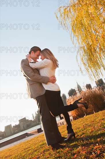 USA, New York, Long Island City, Young couple embracing in park. Photo : Daniel Grill