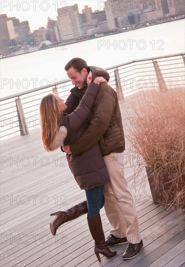 USA, New York, Long Island City, Young couple embracing on boardwalk. Photo : Daniel Grill