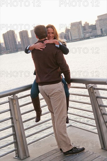 USA, New York, Long Island City, Young couple embracing on boardwalk. Photo : Daniel Grill