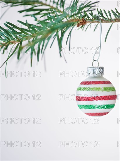 Studio shot of striped Christmas ornament hanging on Christmas tree. Photo : Daniel Grill