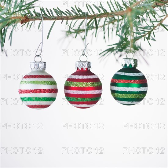 Studio shot of striped Christmas ornaments hanging on Christmas tree. Photo : Daniel Grill