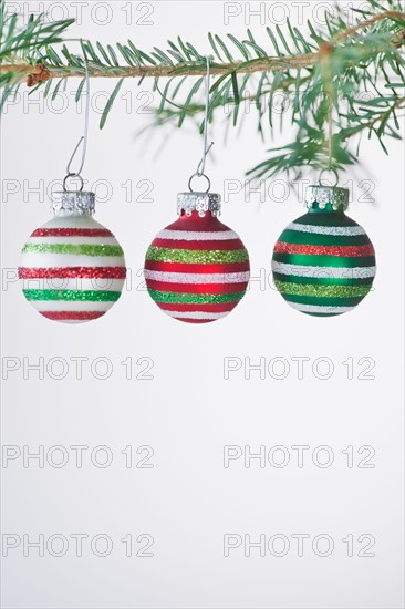 Studio shot of striped Christmas ornaments hanging on Christmas tree. Photo : Daniel Grill