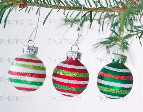 Studio shot of striped Christmas ornaments hanging on Christmas tree. Photo : Daniel Grill