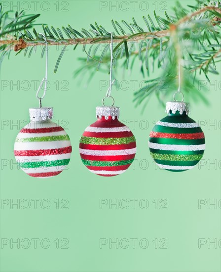 Studio shot of striped Christmas ornaments hanging on Christmas tree. Photo : Daniel Grill