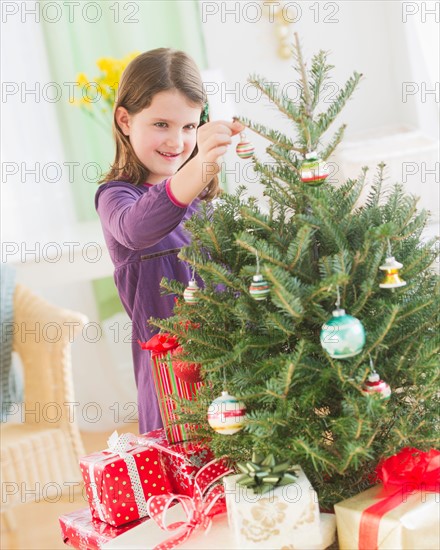 Girl (8-9) hanging decorations on Christmas tree. Photo : Daniel Grill