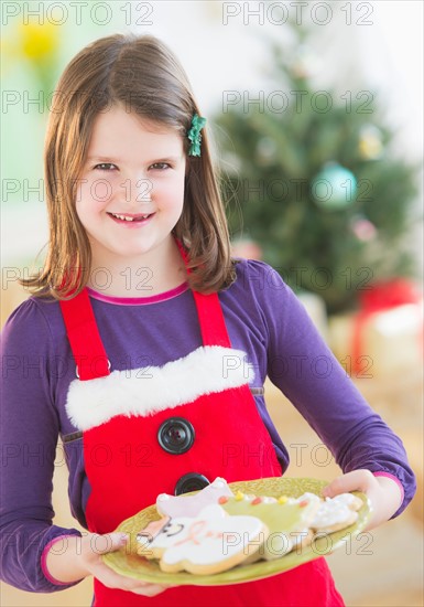 Girl (8-9) holding plate with gingerbread cookies. Photo : Daniel Grill