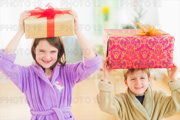 Girl (8-9) and boy (6-7) carrying christmas gifts on their heads. Photo : Daniel Grill