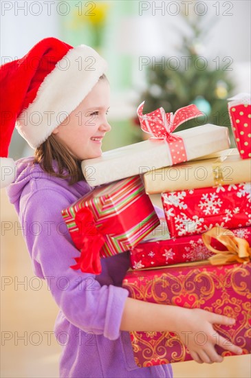 Girl (8-9) carrying christmas gifts. Photo : Daniel Grill