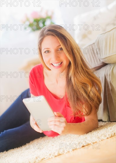 Portrait of young woman working with digital tablet in living room. Photo : Daniel Grill