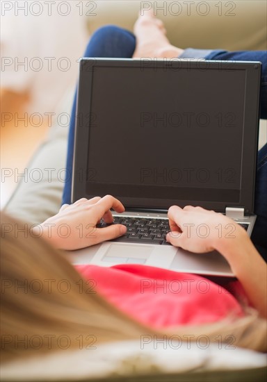 Portrait of young woman with laptop in living room. Photo : Daniel Grill