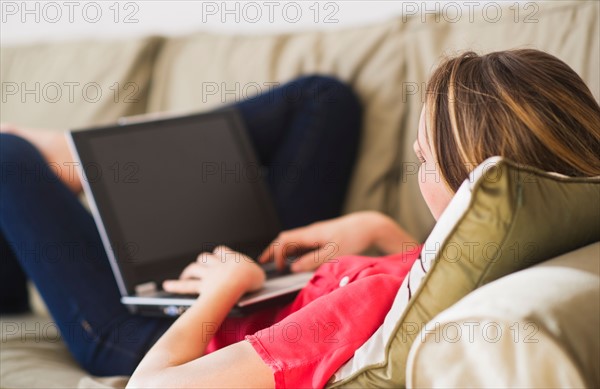 Portrait of young woman with laptop in living room. Photo : Daniel Grill