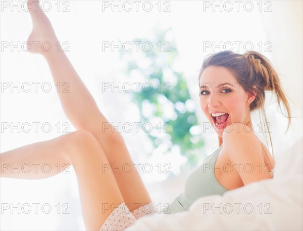 Portrait of young woman lying on bed in bedroom. Photo : Daniel Grill