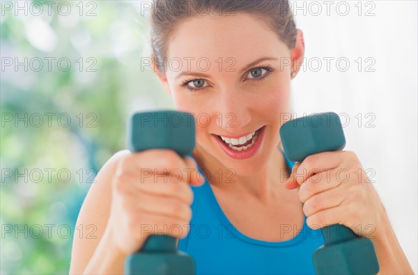 Portrait of young woman with dumbbells. Photo : Daniel Grill