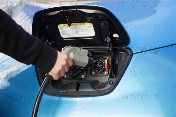 Close-up of man charging electric car. Photo : fotog
