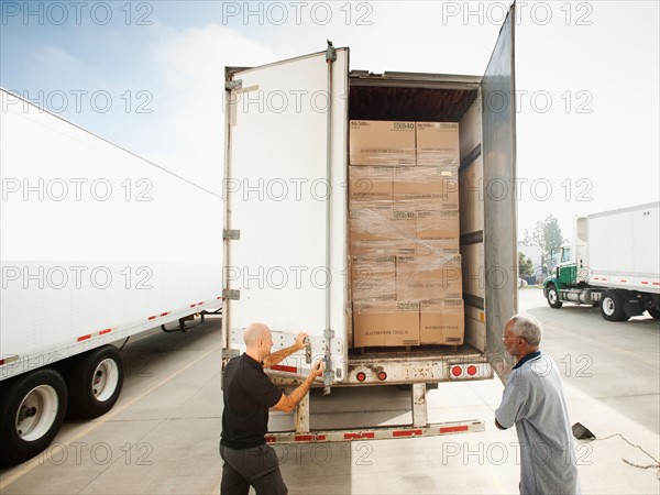 Two men close in truck trailer.