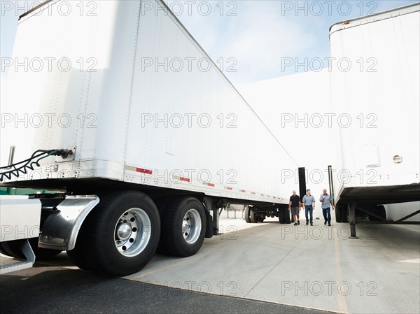 Three men walking between trucks.