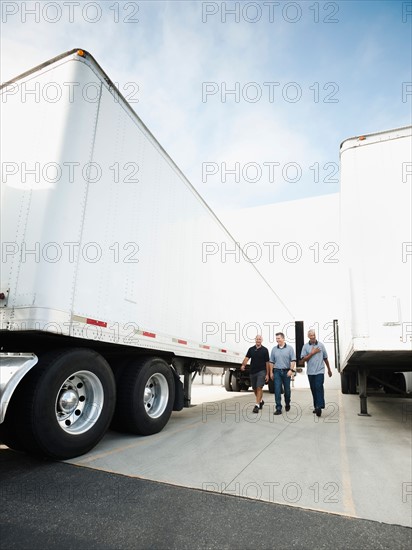 Three men walking between trucks.