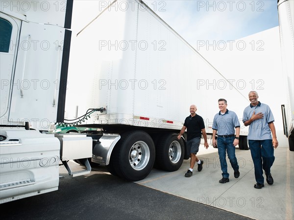 Three men walking between trucks.