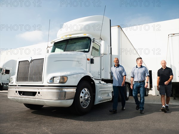 Three men walking between trucks.