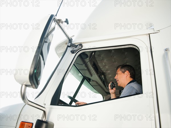Truck driver sitting in truck and talking on CB radio.