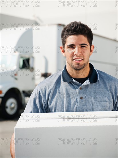 Man carrying box in warehouse.