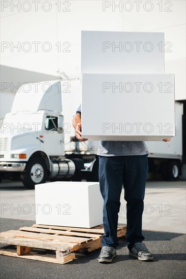 Warehouse worker carrying stack of boxes.