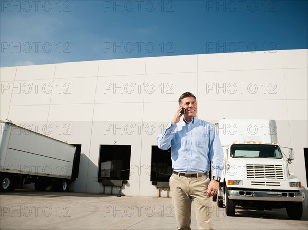 Businessman talking on phone outside warehouse.