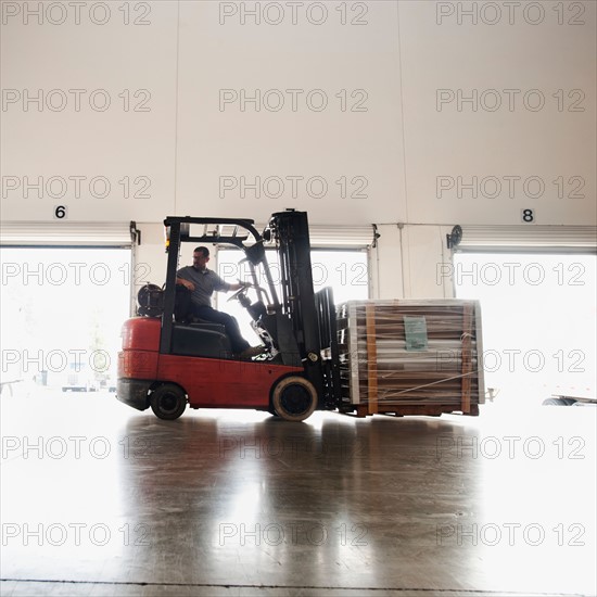 Forklift driver working in warehouse.