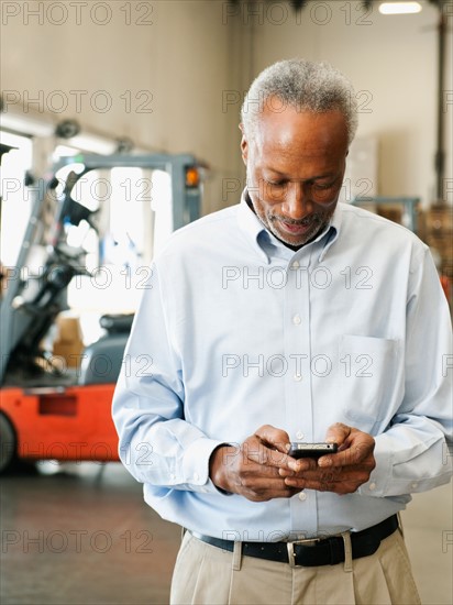 Businessman using phone in warehouse.