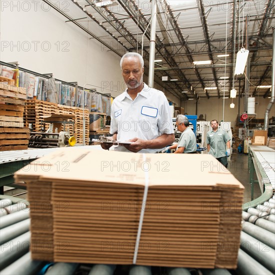 Worker inspecting bundle on conveyor belt.