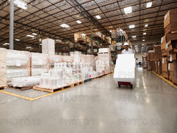 Man pushing hand truck in warehouse.