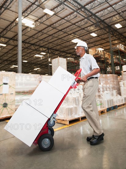 Man pushing hand truck in warehouse.