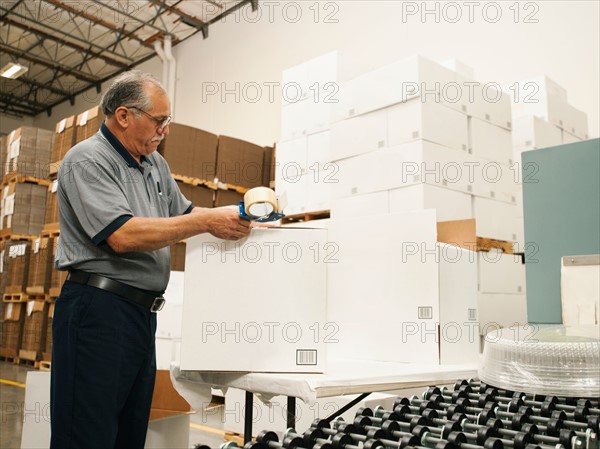 Warehouse worker sealing boxes.