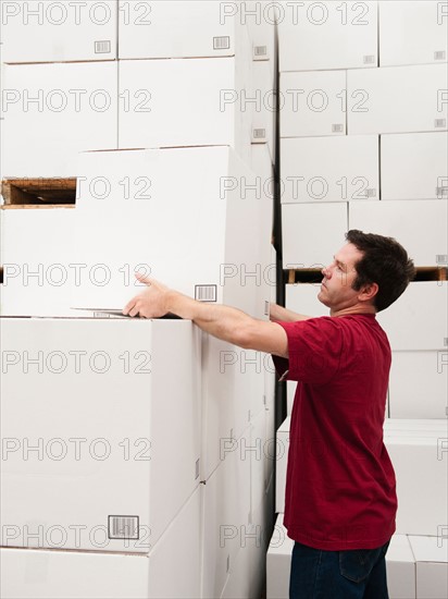 Worker stacking boxes in warehouse.