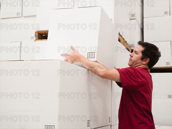 Worker stacking boxes in warehouse.