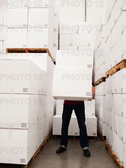 Worker carrying boxes in warehouse.