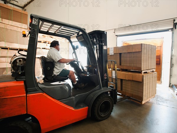 Forklift truck loading pallets into trailer.