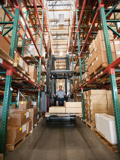 Forklift truck stacking boxes in warehouse.