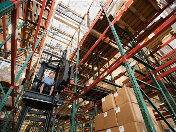 Forklift truck stacking boxes in warehouse.