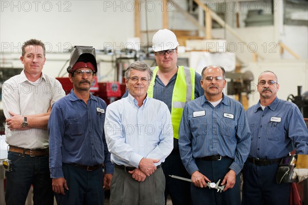 Portrait of businessman and workers in factory.