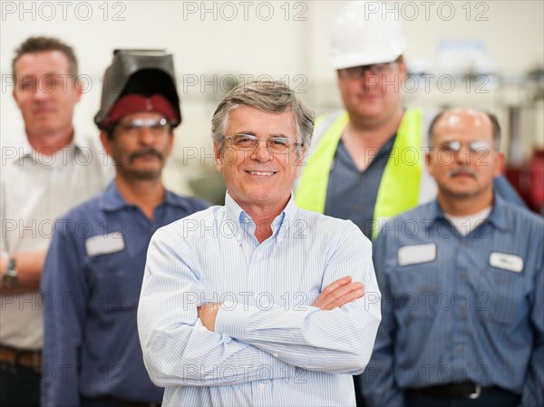 Portrait of businessman and workers in factory.