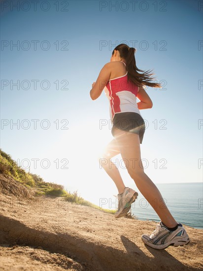 USA, California, San Diego, Woman jogging along sea coast.