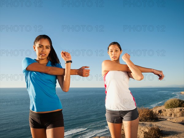 USA, California, San Diego, Two women stretching at sea coast.