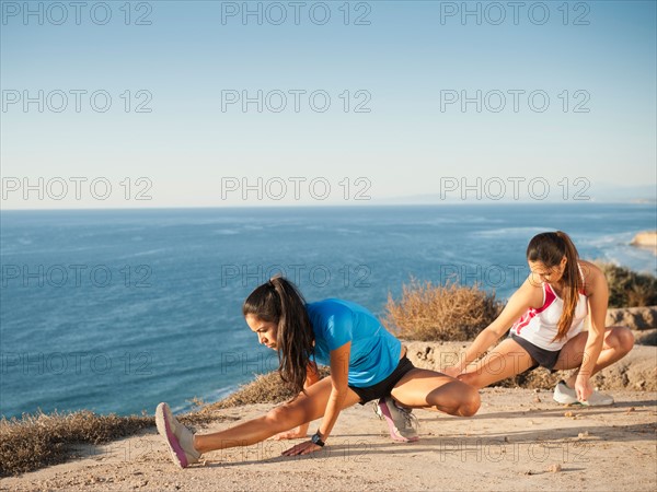 USA, California, San Diego, Two women stretching at sea coast.