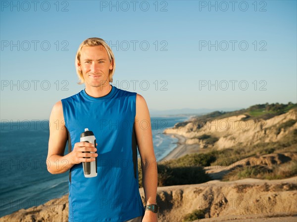 USA, California, San Diego, Portrait of male jogger holding water bottle.